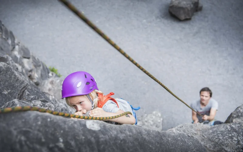 child-climbing-with-gear-adult-belaying-below-2026-03-25-02-48-48-utc
